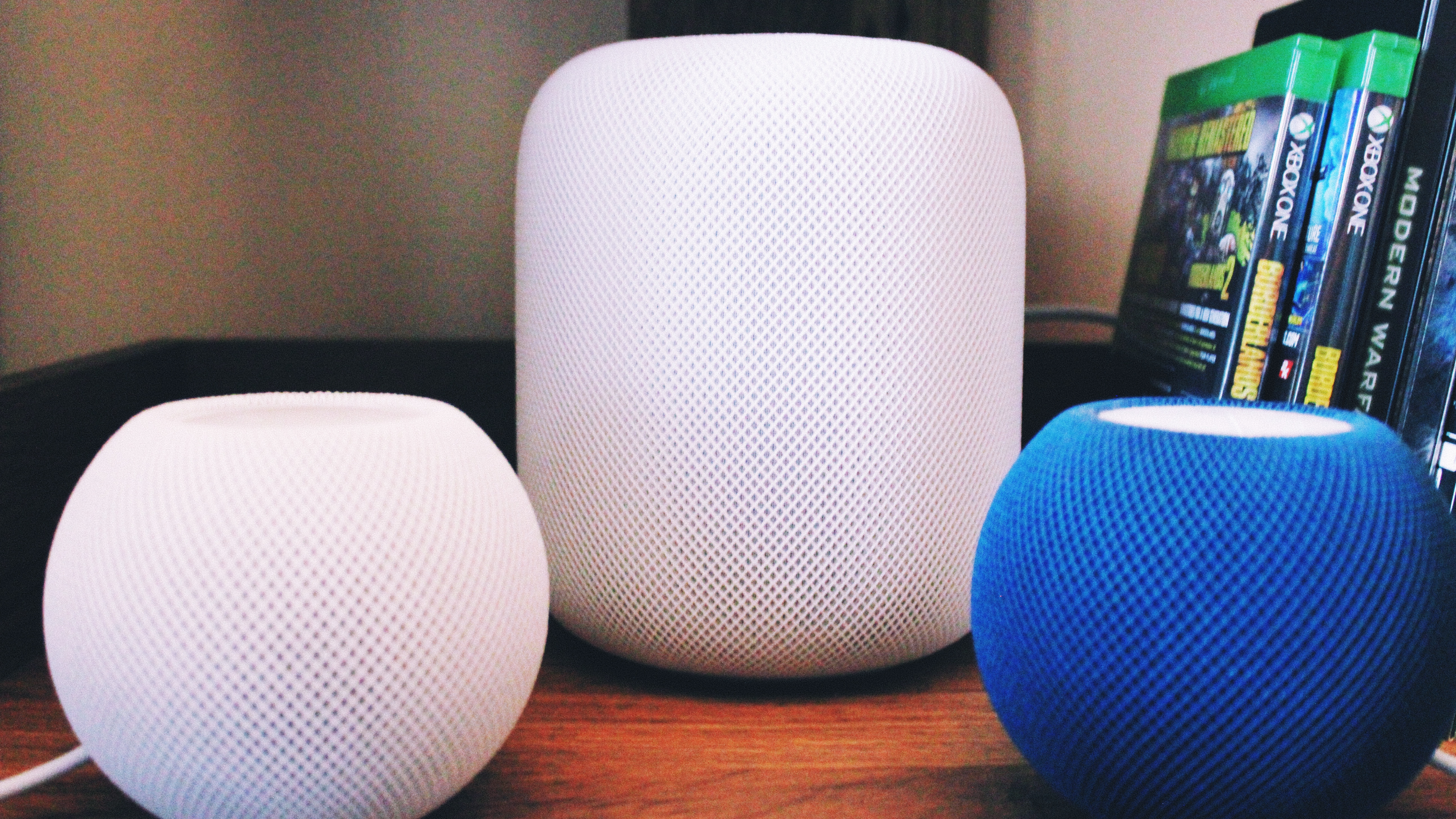 Um Homepod branco ao lado de dois minis homepod, um branco e um azul