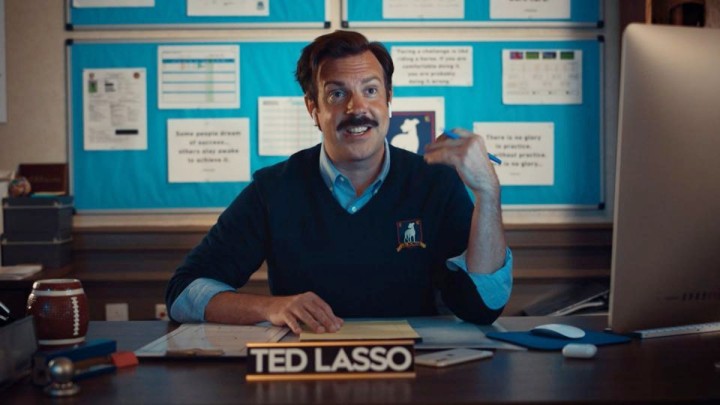 Ted está sentado em sua mesa em Ted Lasso.