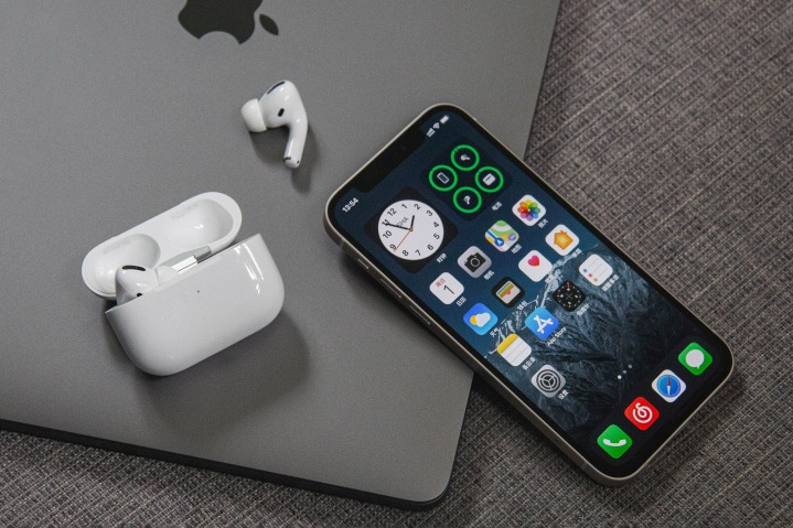 iPhone 12 com AirPods em cima do MacBook.