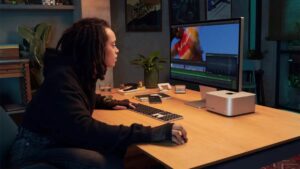 A woman using the Apple Studio Display while sitting at a desk