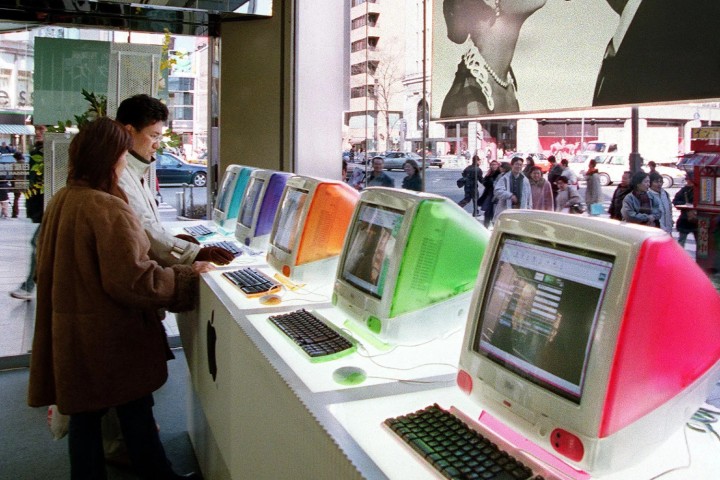 Os clientes olham para uma fileira de computadores iMac G3 de cores vivas em uma Apple Store.