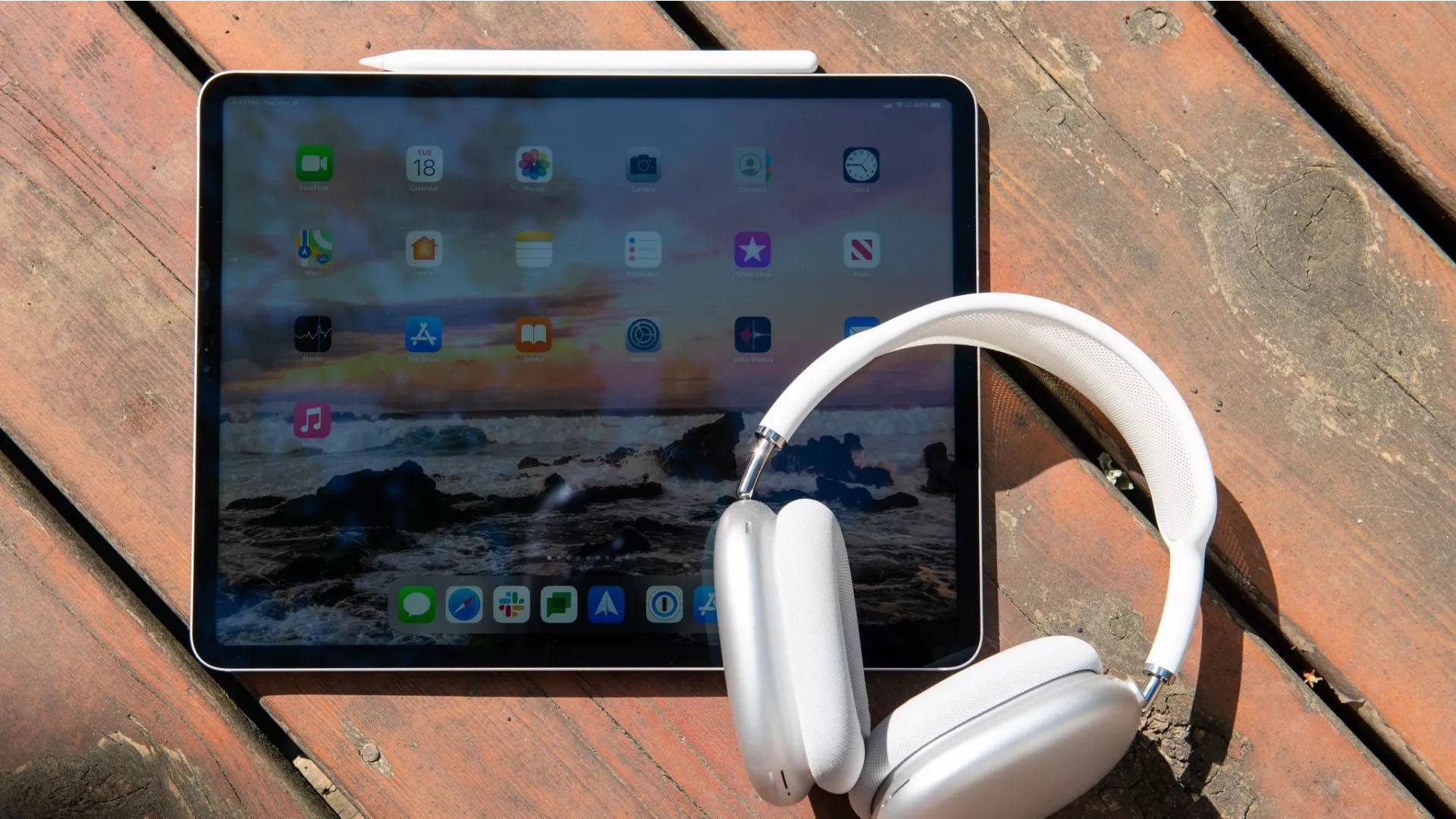 Um iPad Pro em uma mesa ao lado de um par de fones de ouvido