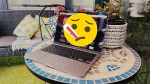 Apple MacBook thats got a sad, sick emoji on it