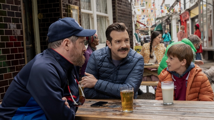 Treinador Beard, Ted e Henry sentados em um pátio em uma cena de Ted Lasso.