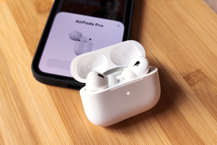 Apple AirPods Pro 2 dentro do estojo de carregamento, perto do iPhone 14.