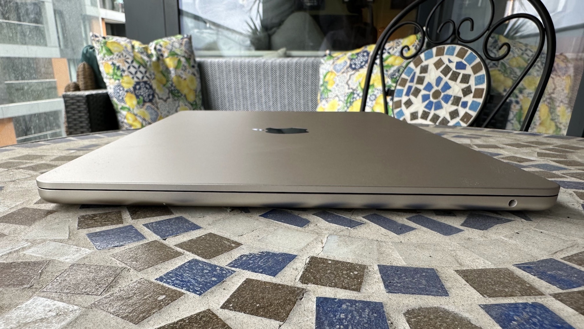 Em casa com o MacBook Air de 15 polegadas, sobre uma mesa de varanda em mosaico e piso de madeira.