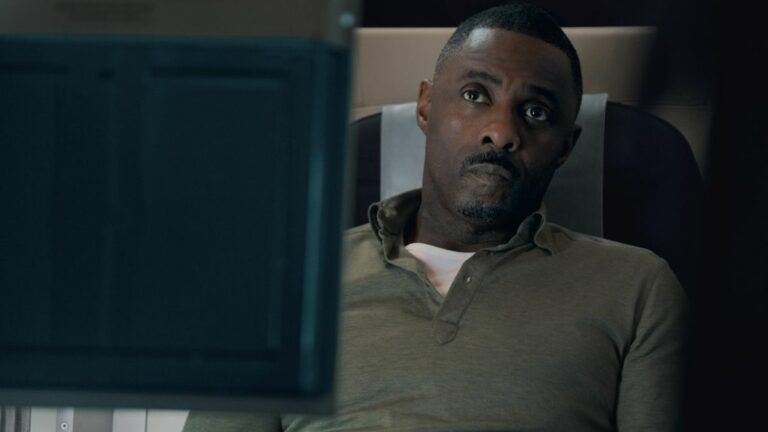 Edris Elba sitting in an airline seat on Apple TV Plus