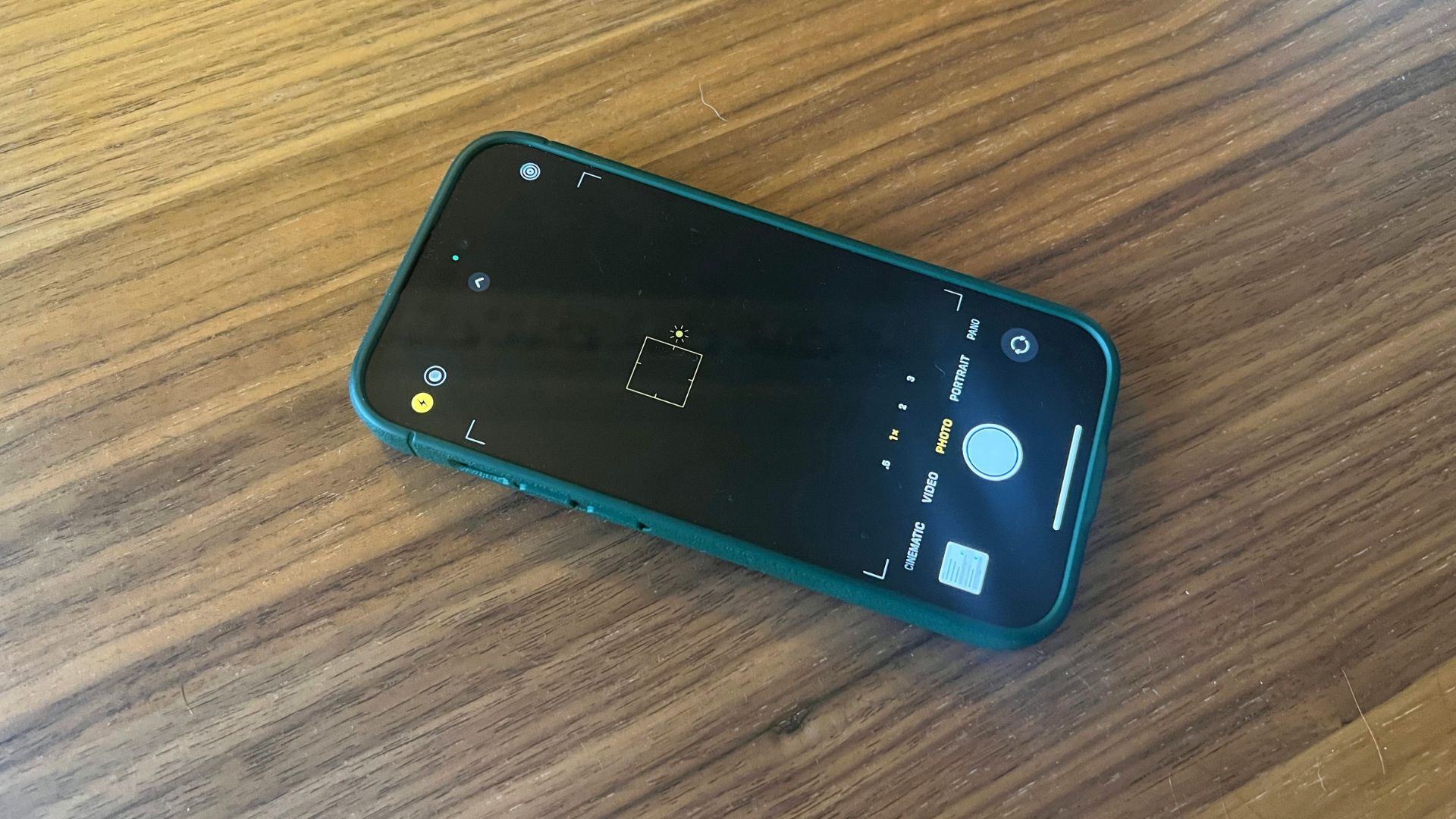 iPhone 14 Pro com aplicativo de câmera na tela sentado na mesa de madeira