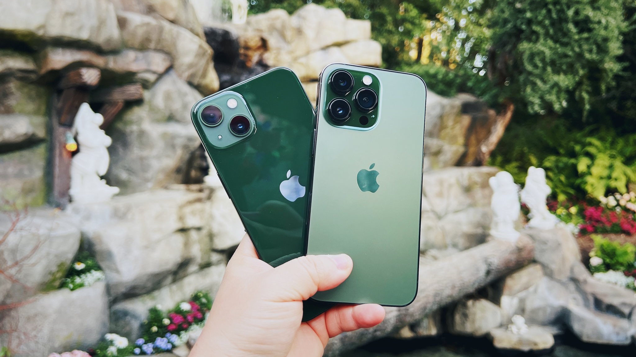 Green iPhone 13 e Alpine Green iPhone 13 Pro segurados na frente da fonte Branca de Neve na Disneyland, CA