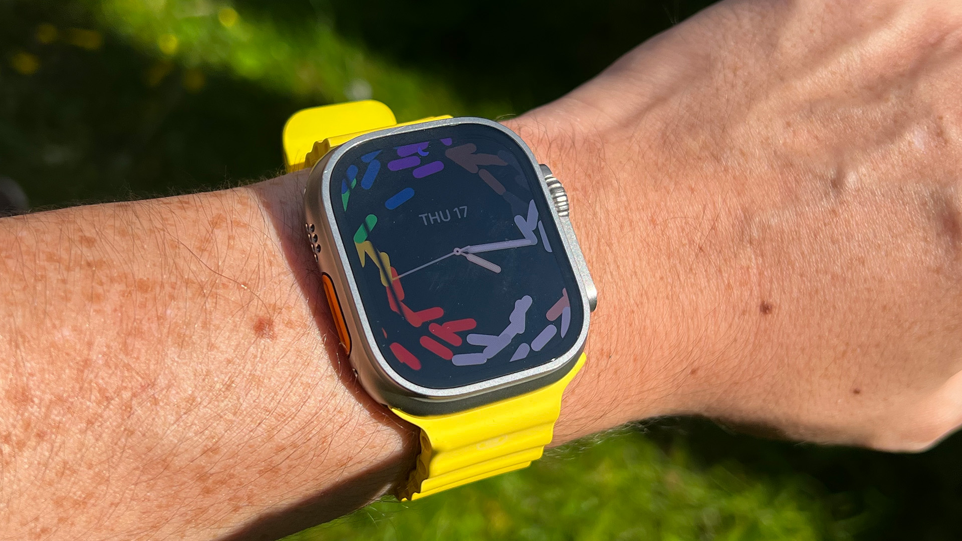 Apple Watch Ultra com faixa amarela no jardim
