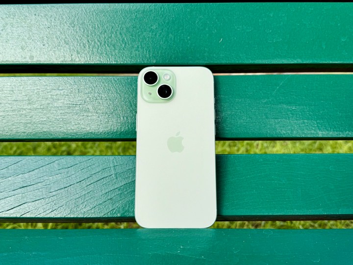 Um iPhone 15 verde em um banco verde.