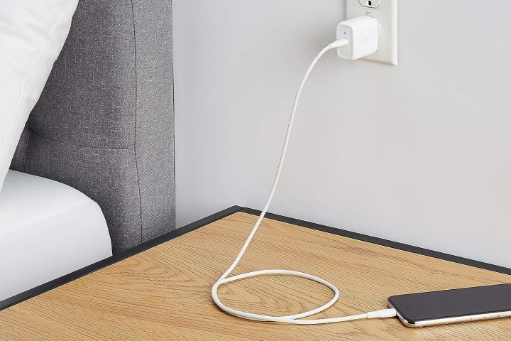 Carregador USB-C GaN de uma porta de 30 W do Amazon Basics conectado próximo a uma mesa onde o telefone está sendo carregado.