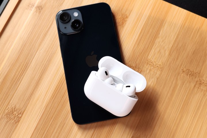 Apple AirPods Pro 2 dentro do estojo de carregamento, na parte traseira de um iPhone 14.