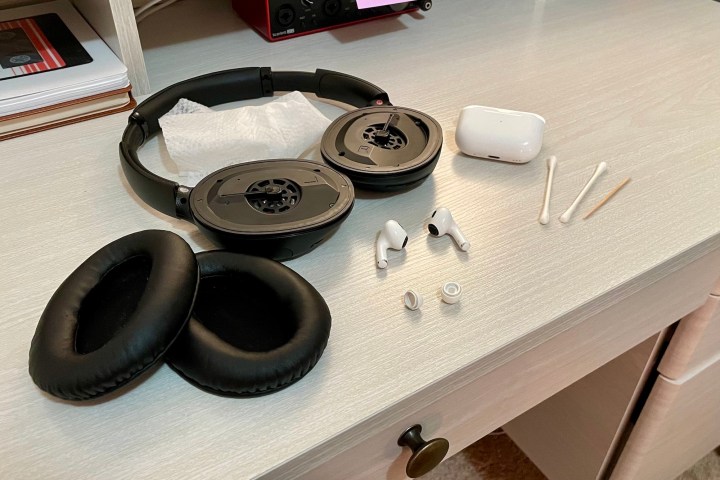 Fones de ouvido, fones de ouvido e materiais de limpeza em uma mesa.