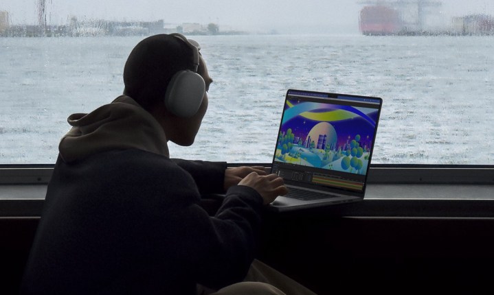 Alguém usando um MacBook Pro em uma mesa em frente a um cenário panorâmico.