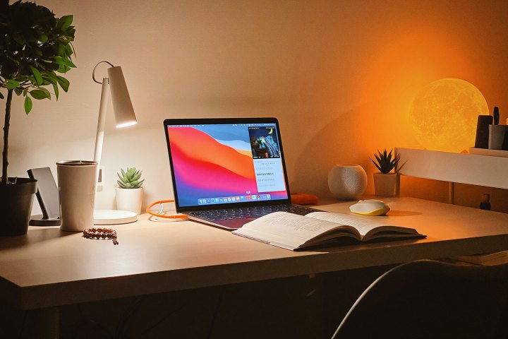 Um MacBook Air em uma mesa com um livro aberto na frente.