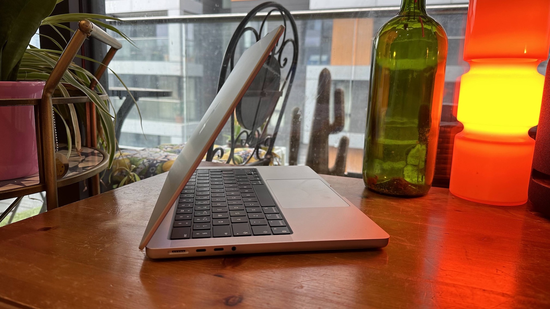 Um MacBook Pro 2023 de 14 polegadas em um balcão de madeira, perto de uma lâmpada retrô.