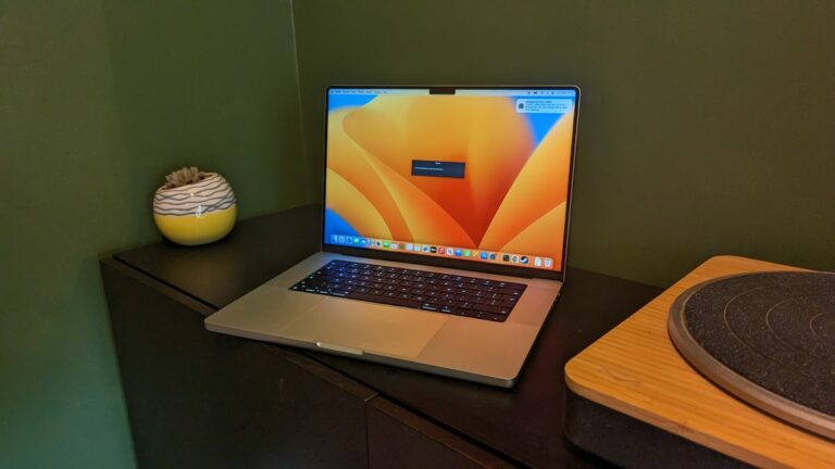 MacBook Pro 16-inch (2023) on wooden desk with green background