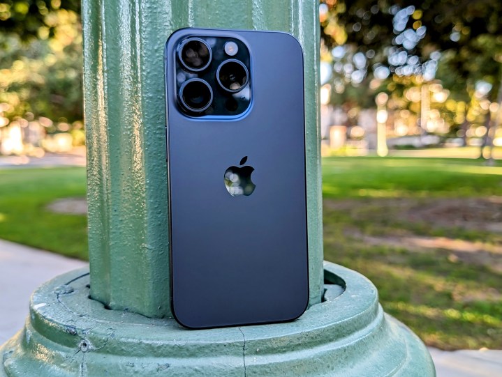 Blue Titanium iPhone 15 Pro apoiado em um poste de luz do parque.