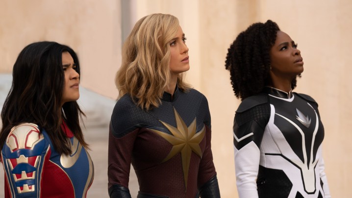 Iman Vellani, Brie Larson e Teyonah Parris olham para algo fora da tela.