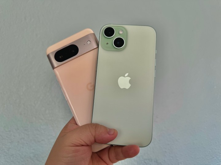 Um Google Pixel 8 rosa (esquerda) na mão com um iPhone 15 verde.