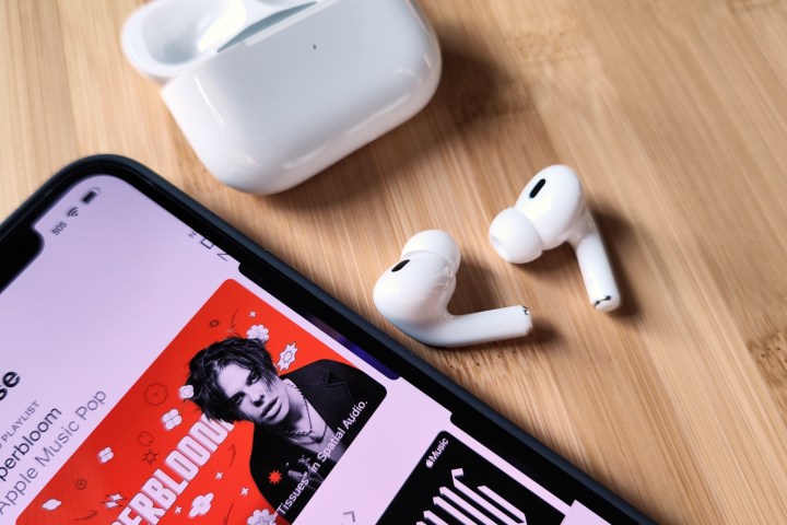 Apple AirPods Pro 2 ao lado do iPhone 14 e do estojo de carregamento.