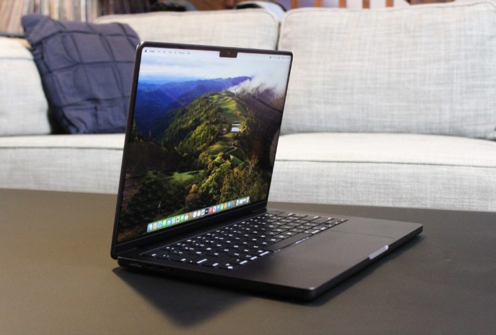 O MacBook Pro aberto em uma mesa em frente a um sofá.