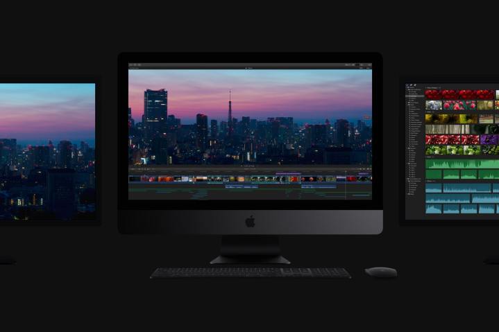 Um Apple iMac Pro em uma sala escura ladeada por dois monitores, um de cada lado.