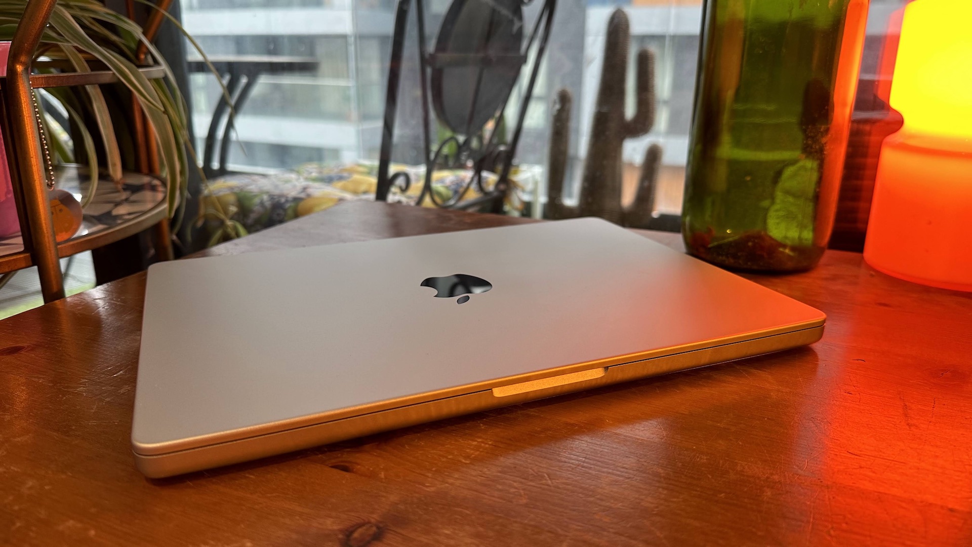 Um MacBook Pro 2023 de 14 polegadas em um balcão de madeira, perto de uma lâmpada retrô.