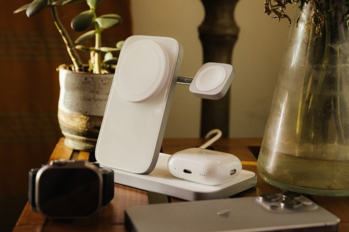 Suporte de carregamento Silver Nomad Stand One Max para iPhone na mesa com AirPods Pro, iPhone e Apple Watch na frente.