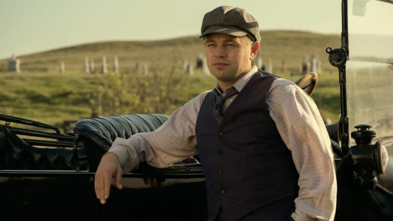 Leonardo DiCaprio leaning against a car