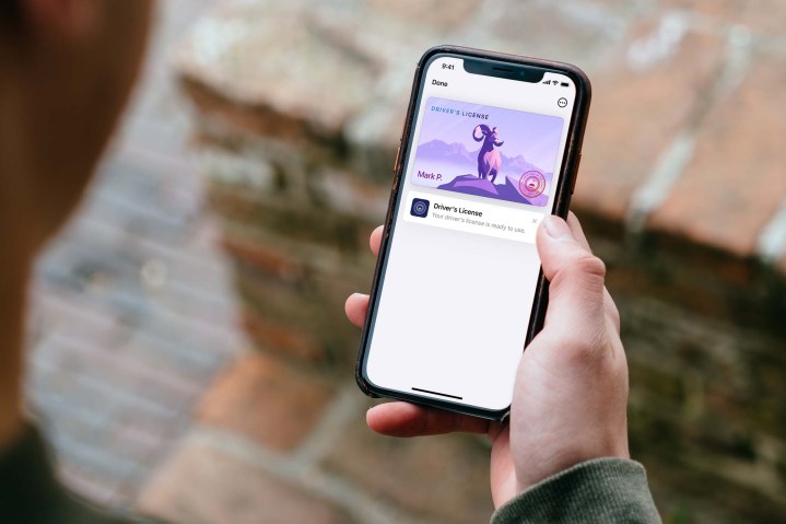 Pessoa que acessa um documento de identidade estadual usando a Apple Wallet em um iPhone.