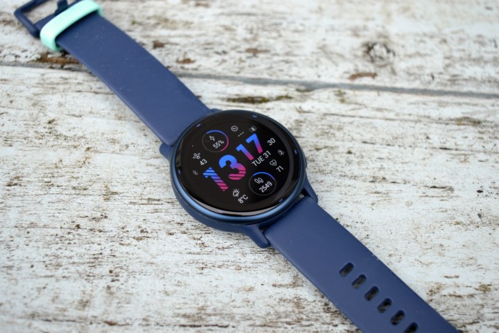 O Garmin Vivoactive 5 colocado sobre madeira pintada, voltado para cima.