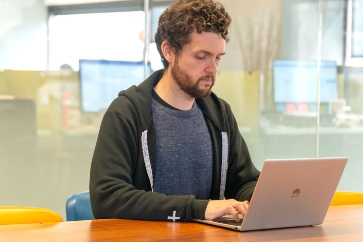 Uma pessoa digitando em um laptop Huawei MateBook X Pro em uma mesa.