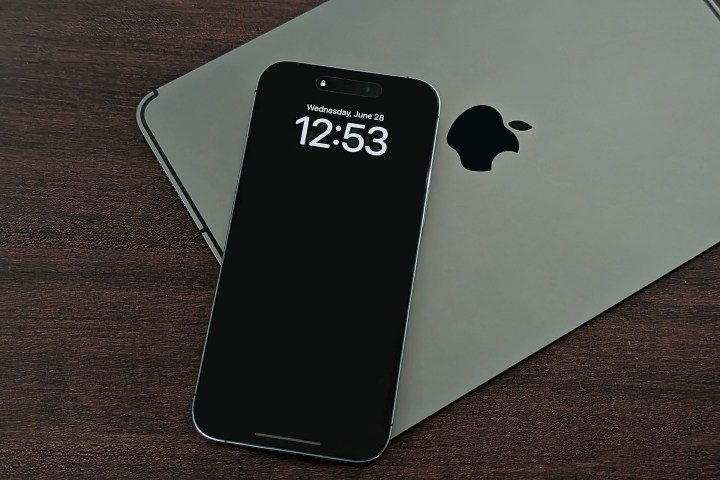 iPhone 14 Pro Max colocado em cima do iPad mostrando tela sempre ativa com papel de parede desativado.
