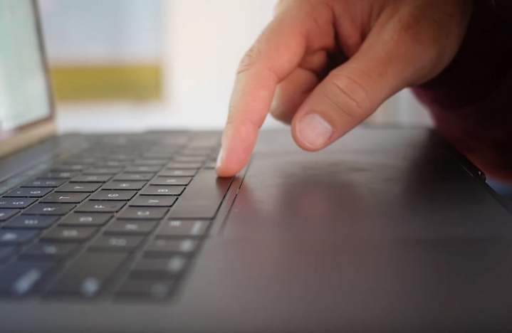 Vista lateral do Apple MacBook Pro mostrando o dedo no teclado.