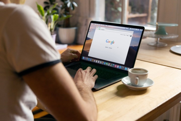 Uma pessoa na página inicial do Google enquanto usa um laptop MacBook Pro em uma mesa.