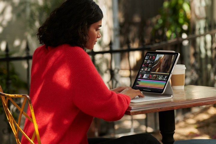Uma pessoa usa um M1 iPad Pro com capa de teclado enquanto está sentada em uma mesa.