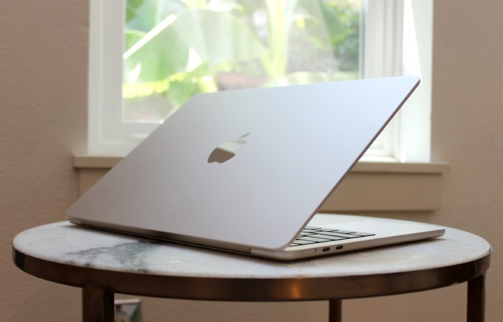 O MacBook Air em uma mesa em frente a uma janela.