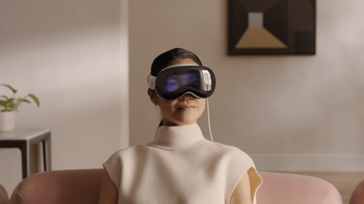 Uma mulher usa o headset Apple Vision Pro enquanto está sentada em um sofá.