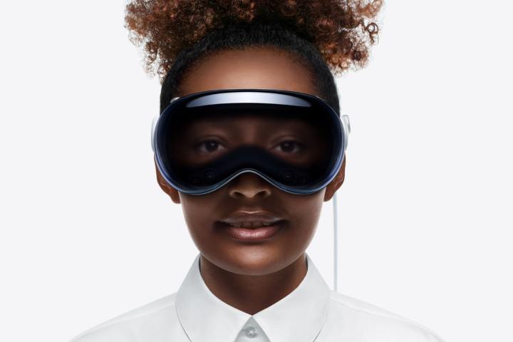 Uma pessoa usa um headset Apple Vision Pro.  Seus olhos são visíveis pela parte frontal do dispositivo.