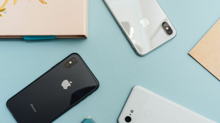 a grey, black and white iphone face down against a light blue background