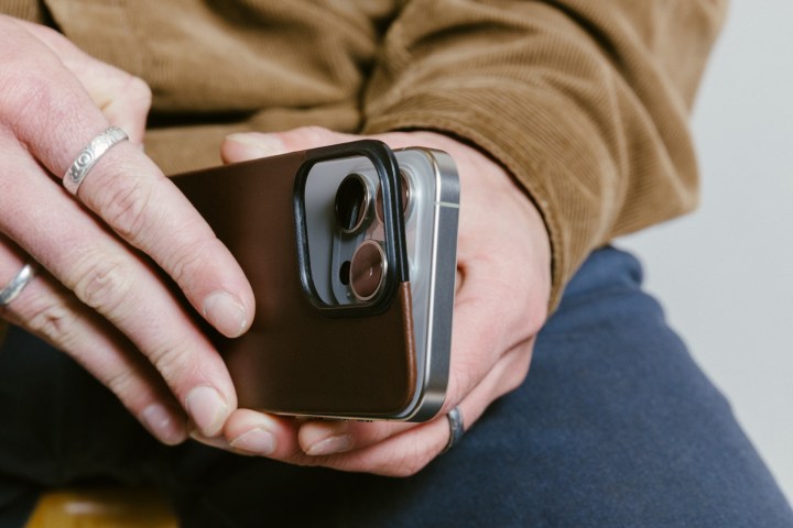 Pessoal removendo a parte traseira de couro magnético Rustic Brown Nomad do iPhone 15 Pro.