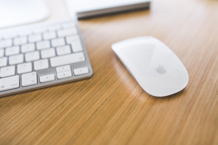 Magic Mouse ao lado de um teclado Mac em uma mesa.