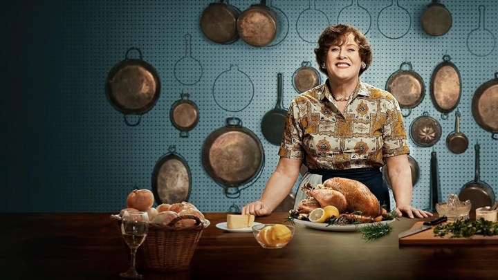 Julia Child parada atrás de uma mesa cheia de pão em cena de Julia.