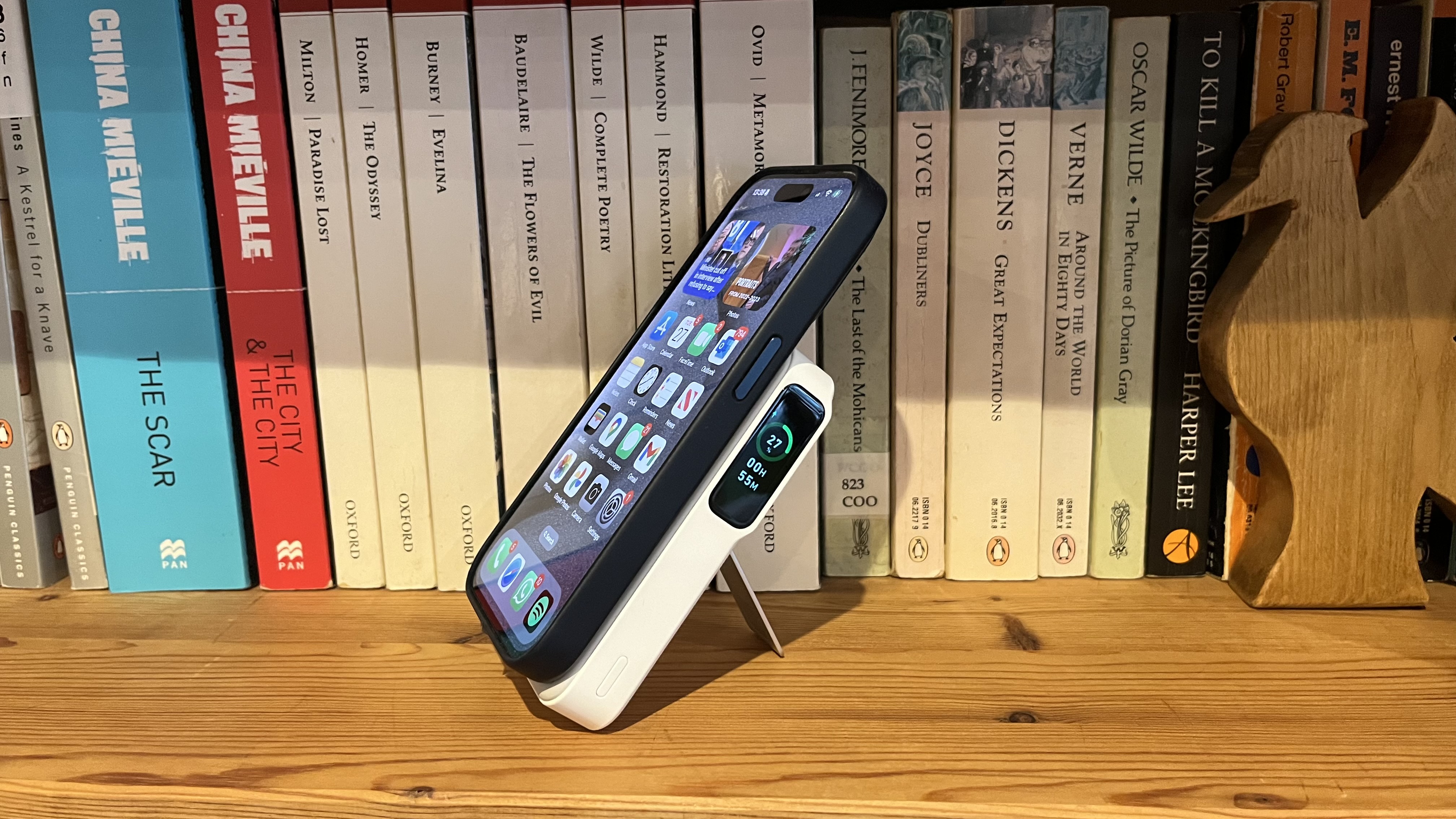 O Anker MagGo Power Bank (10K) conectado a um iPhone 15 Pro em uma estante de madeira