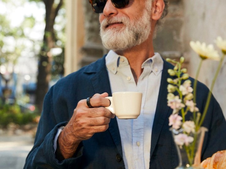 Um homem usa um Oura Ring Gen3 enquanto toma café em uma cafeteria.