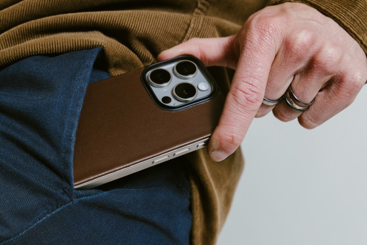 Pessoal tirando o iPhone 15 Pro do bolso com parte traseira de couro magnético Rustic Brown Nomad anexada.