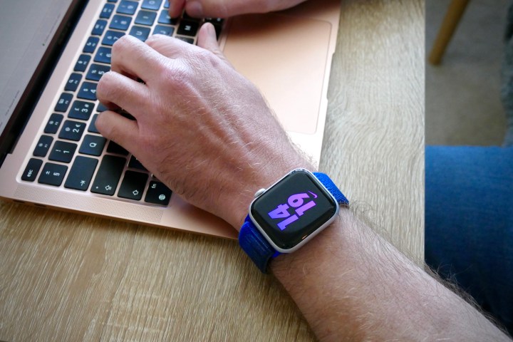 Homem usando o Apple Watch SE 2 e digitando em um MacBook.