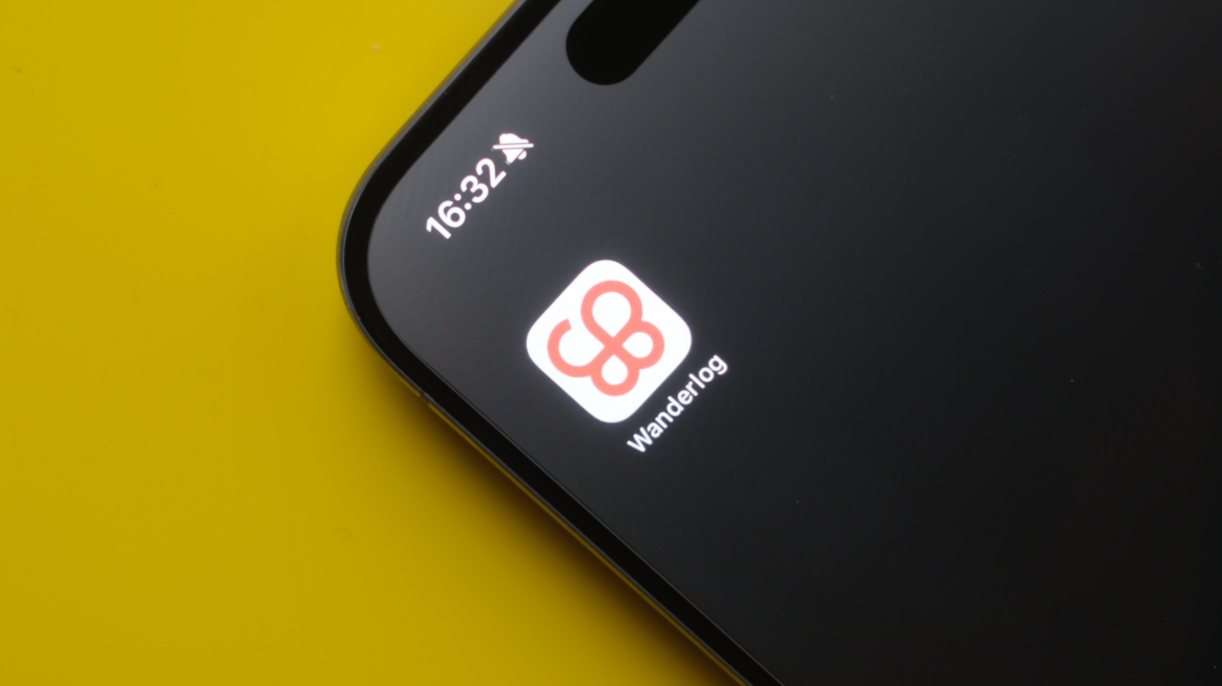 Logotipo do aplicativo Wanderlog em um iPhone 15 Pro Max com fundo amarelo